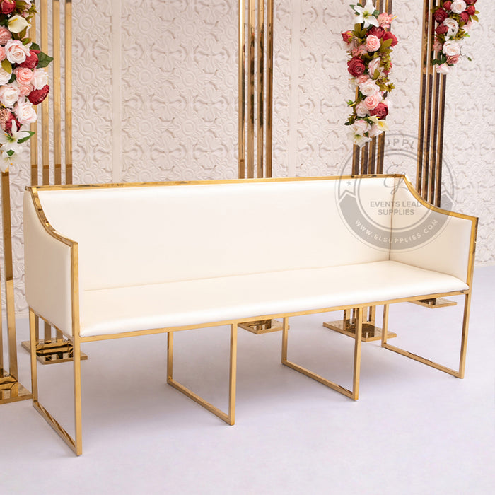 White upholstered sofa with a gold metal frame, placed in front of a floral and patterned backdrop.